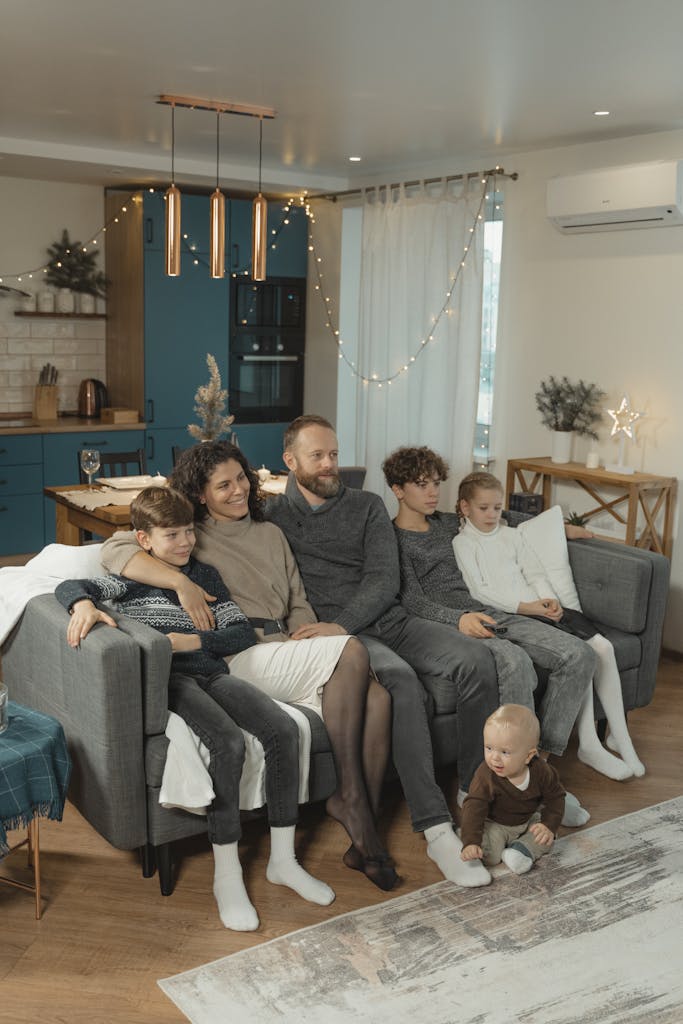 A family sitting together on a couch in a cozy living room setting, creating a warm and inviting atmosphere.